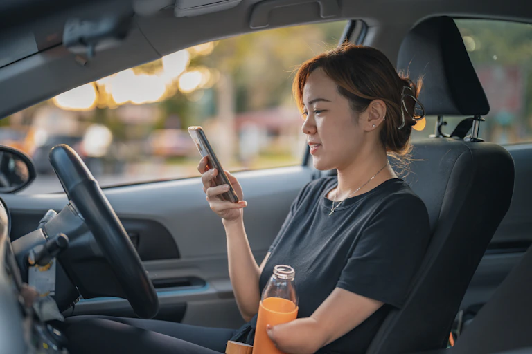 Woman with amputated arm looks at phone in car.