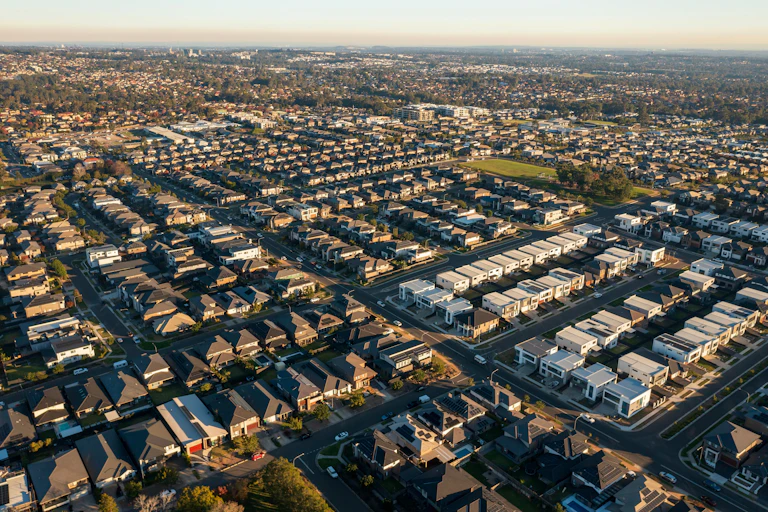 Late afternoon, wide aerial view of streets and similar sized modern Australian homes in Sydney's rapidly growing and increasingly sprawling outer suburbs