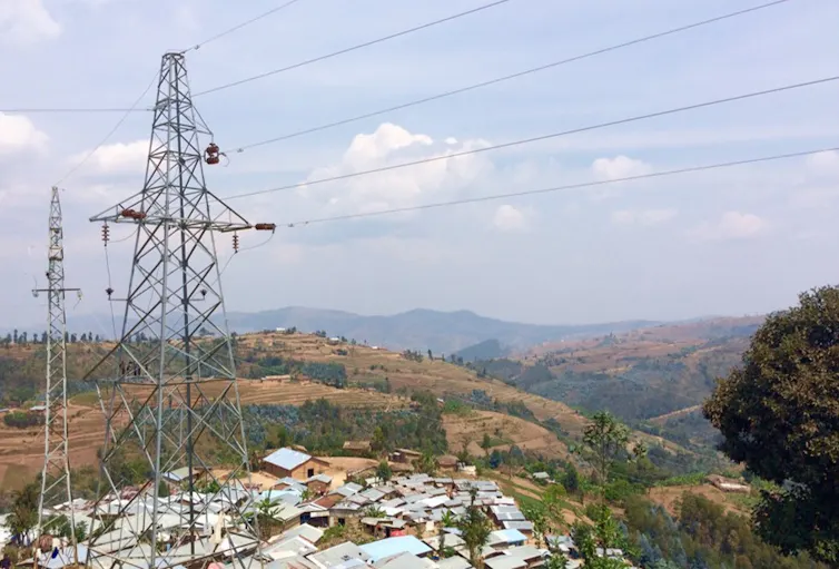 view over shacks with solar panels on roofs, pylon in foreground