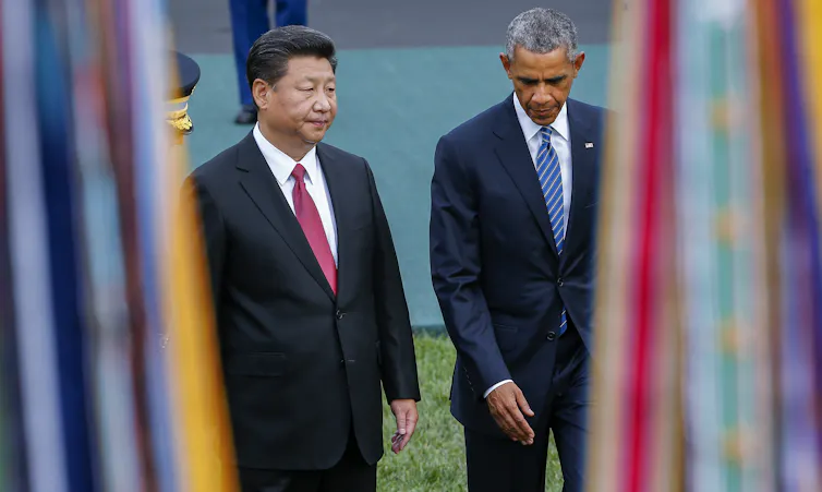 Barack Obama and Xi Jinping walk side by side.