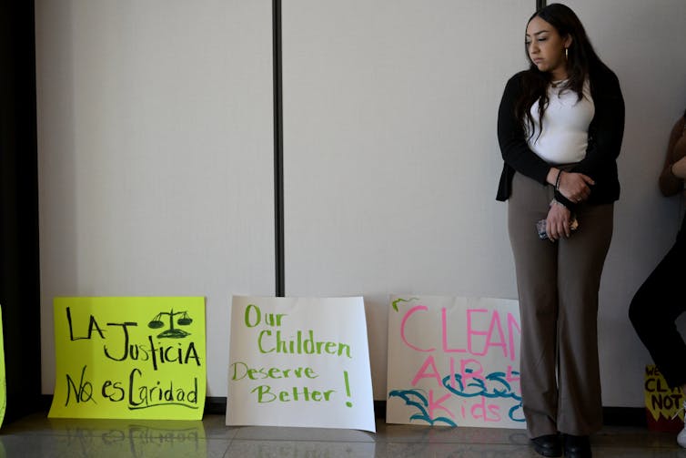 A woman stands in front of posters that call for air pollution justice and