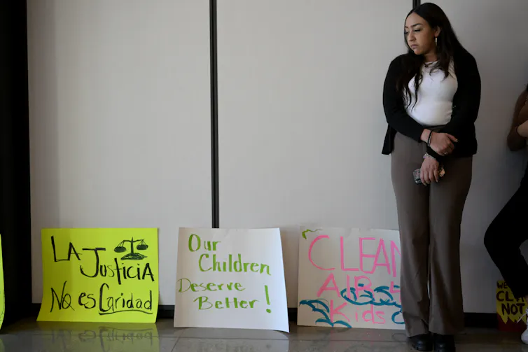 A woman stands in front of posters that call for air pollution justice and