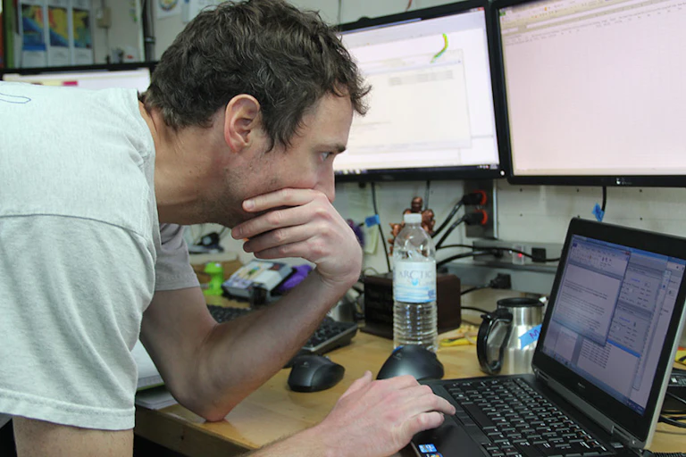 A scientist in a T-shirt works on a computer