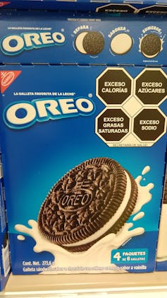 A bag of Oreo cookies with Spanish language packaging, with four black octagons highlighting high calories, fat, sugar and sodium on the front of the package