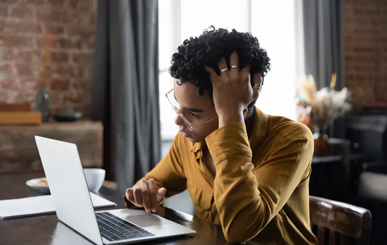 A young woman with a confused expression using a laptop