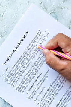 Person filling Non-Compete Agreement Form. View from above