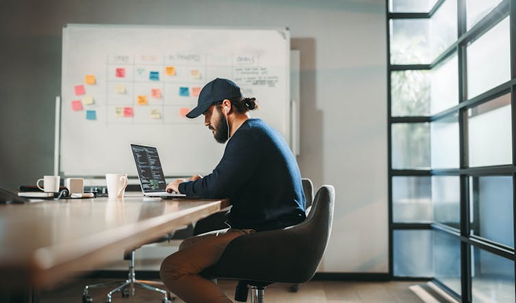 young professional software developer codes on a laptop in a modern office