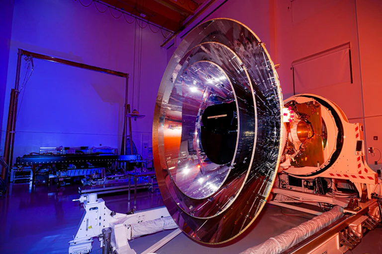 Large megaphone-shaped telescope in a large blue and red lit laboratory.