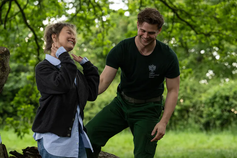 Bridget Jones touching her neck while Rockster helps her.