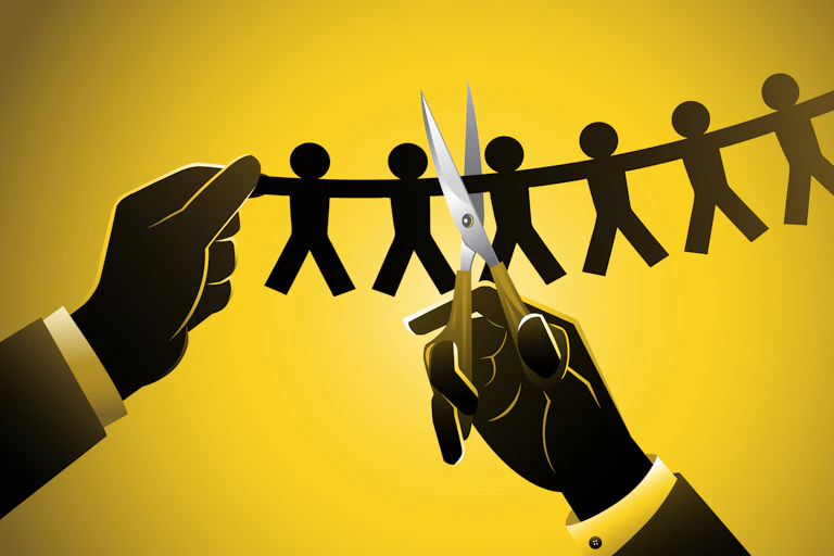 A pair of hands holding scissors cutting a string of paper dolls.