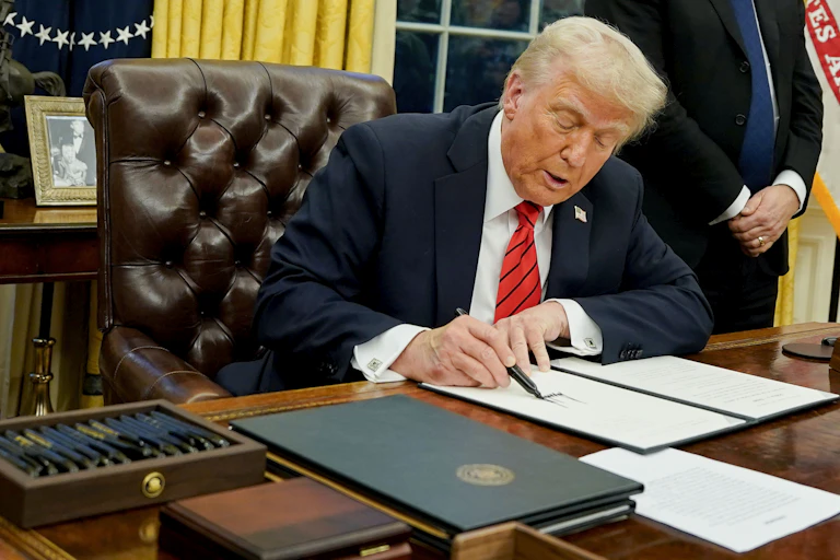 Donald Trump signs an executive order in the Oval Office.