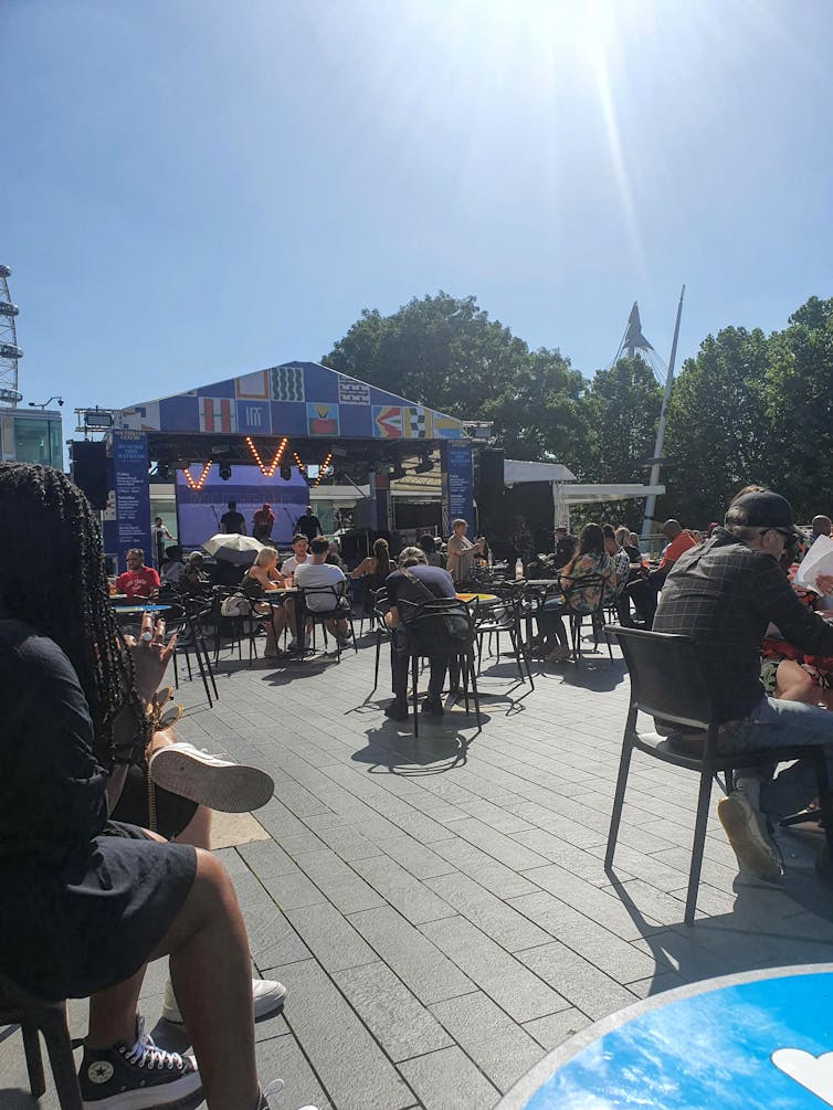 People sat on decking watching music in the sunshine