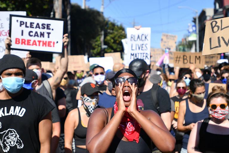 Participants in a BLM protest are seen holding signs and chanting, where some people wore face masks.