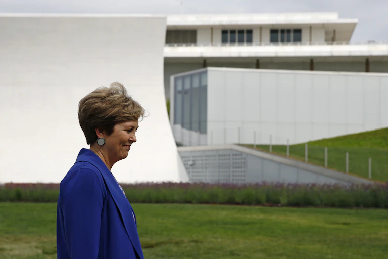 A woman in a blue suit walks by a large white complex.