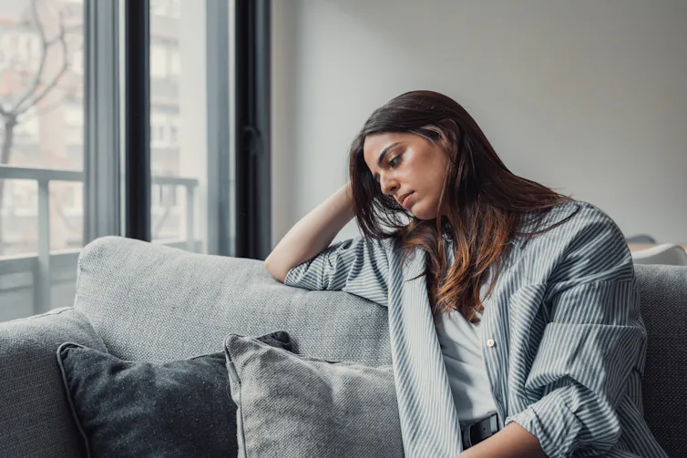 A young woman sitting on a couch appears despondent.