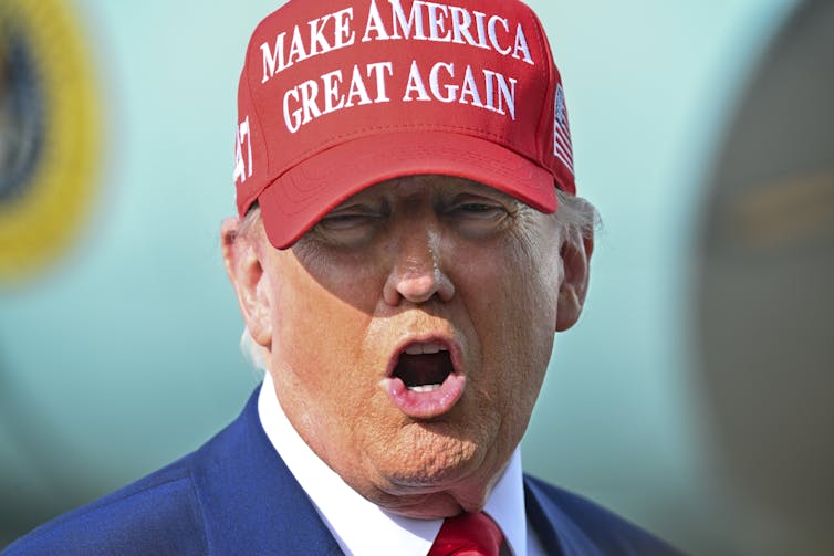 Donald Trump wearing a red MAGA cap.