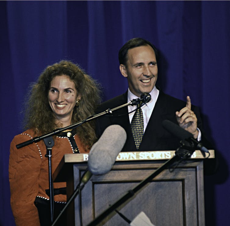 Paul Keating and his wife stand smiling at a podium.