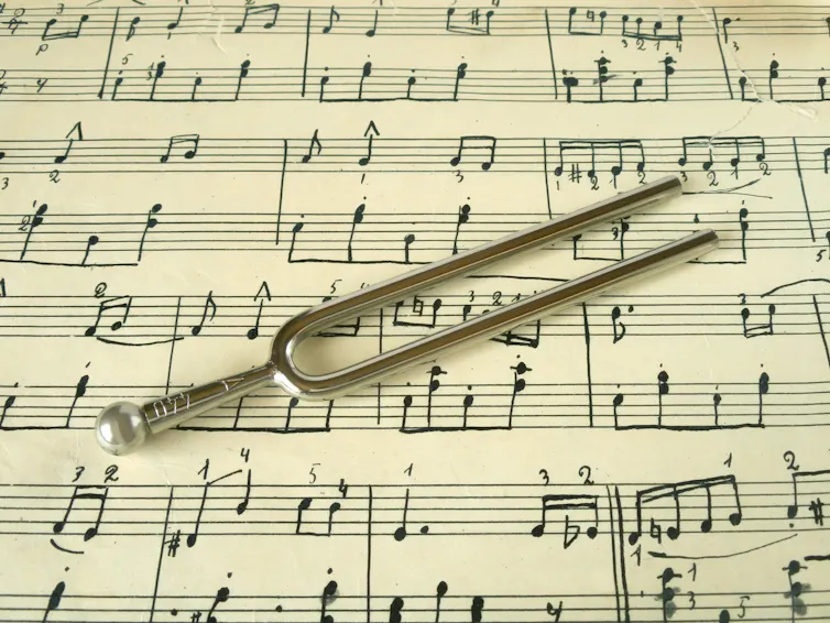 Tuning fork on old sheet music, closeup.