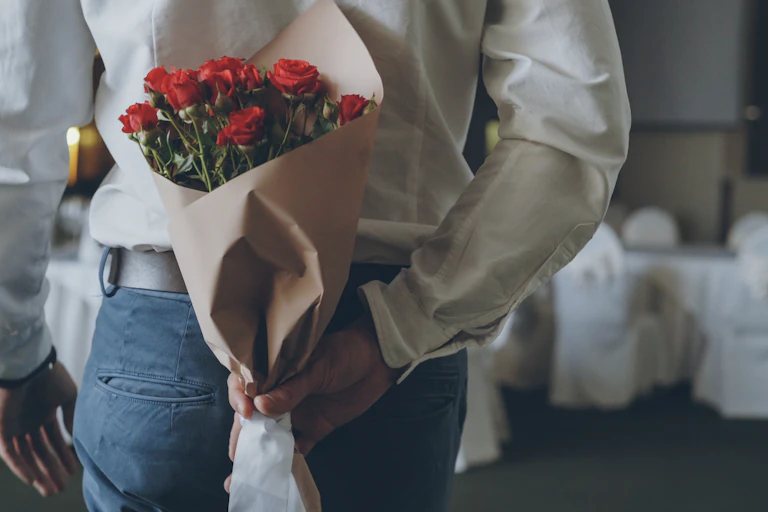 View from behind of a man holding a bouquet of roses behind his back
