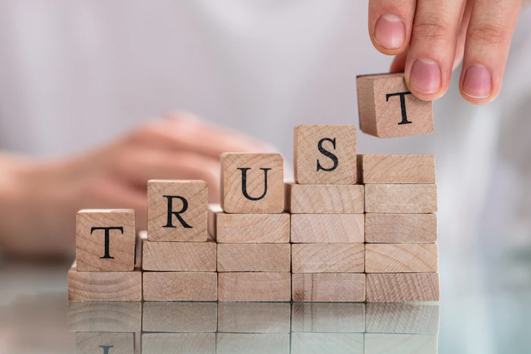 The word "Trust" is spelled out in wooden blocks.
