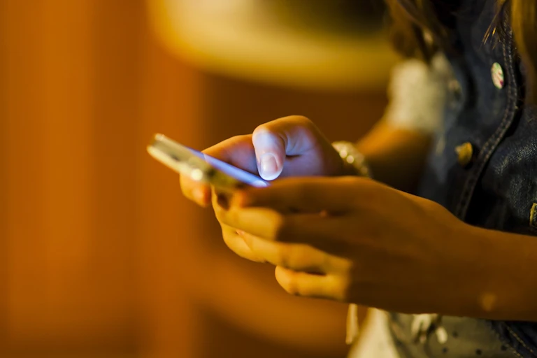 A young person holds a phone.