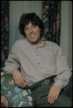 A dark-haired man sitting in a floral armchair.