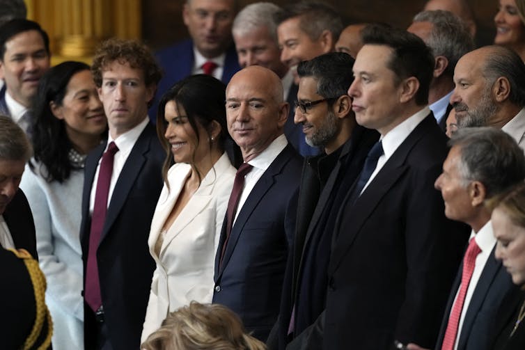 A bald man, Jeff Bezos, stands with a group of tech billionaires at Trump's inauguration.