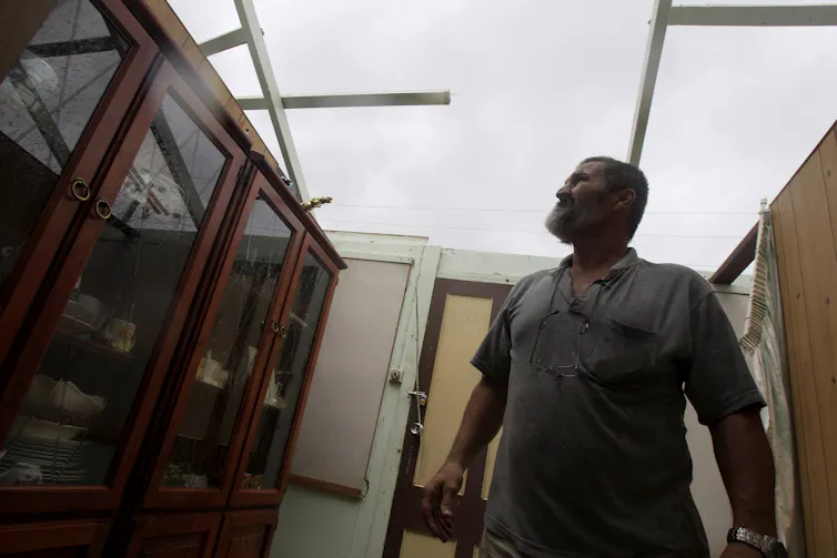 man looks out of roofless home