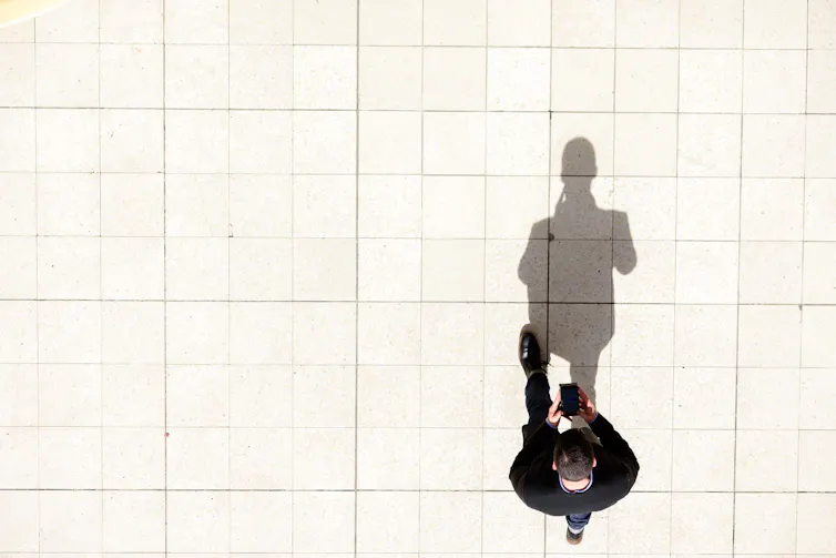 man walking, texting on phone.