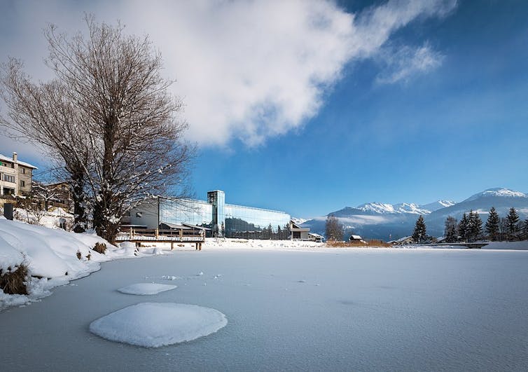 A snowy landscape, a glass building in the background.