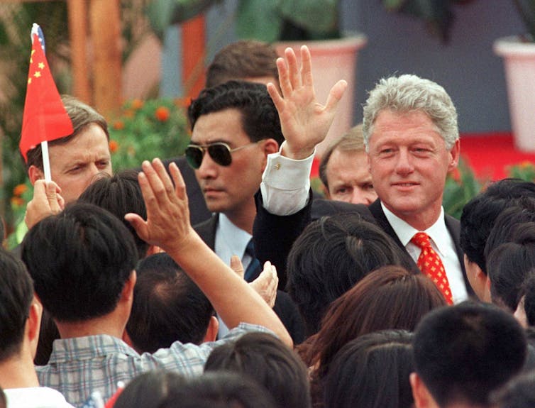 Man in suit waves to a crowd of people.