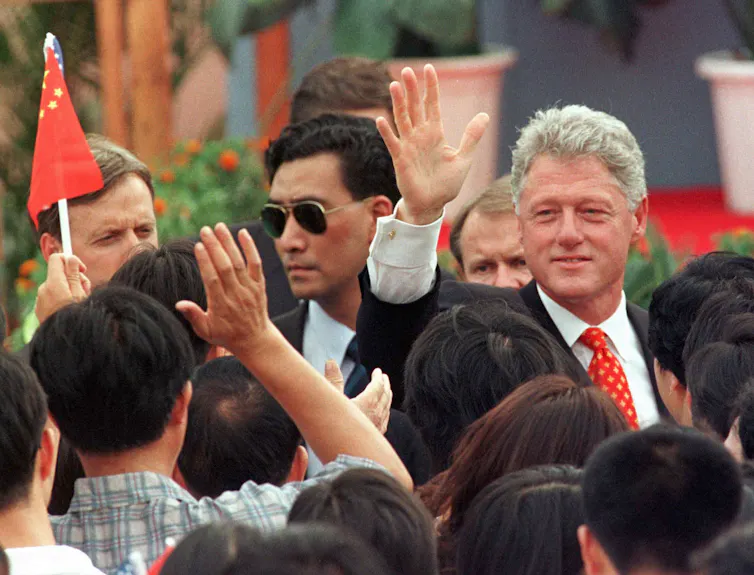 Man in suit waves to a crowd of people.