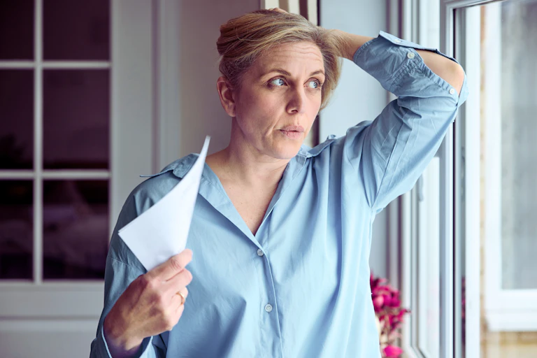 A woman at a window fanning herself.