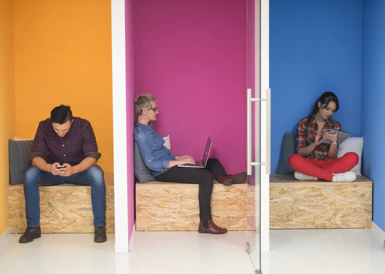 A group of colleagues focusing on their devices in separated office cubicles.