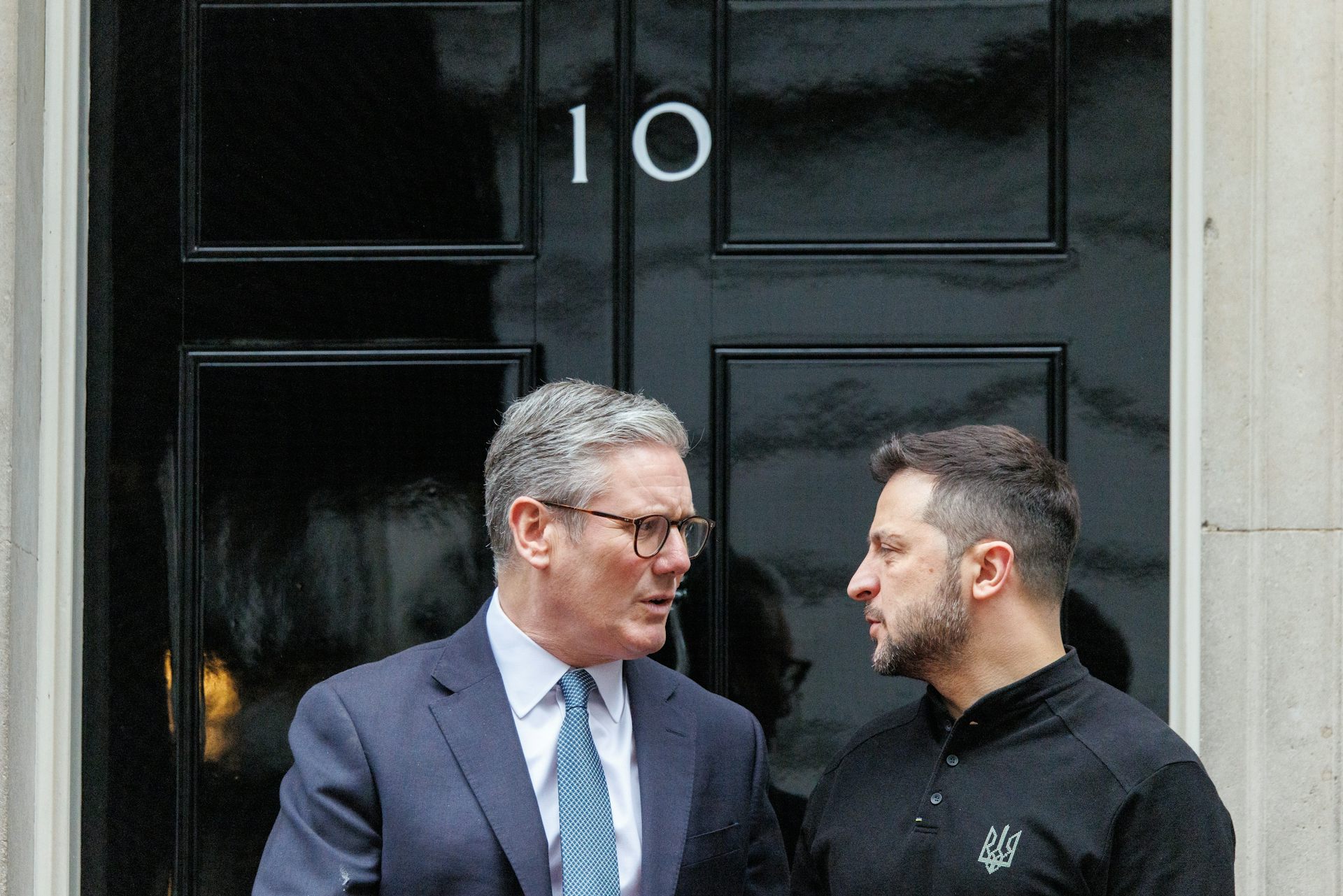 Starmer and Zelensky looking at eachother and talking in front of Downing Street's black door