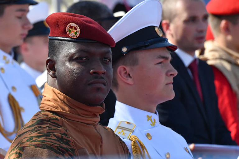 Man in red beret and military uniform, pictured amid other men in military uniforms