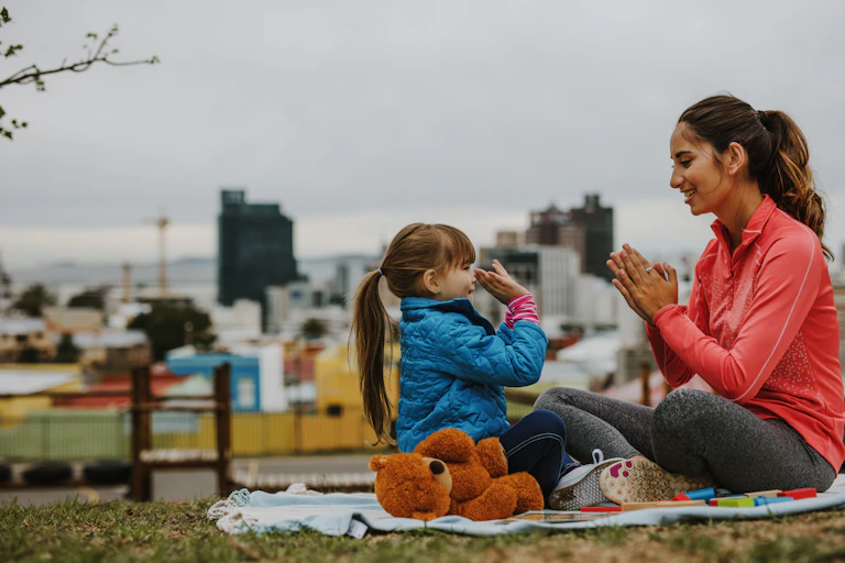 young woman playing in the park with a little girl