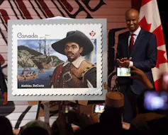 Stamp featuring a Black man in 17th century floppy hat being presented by a Black man in a suit.