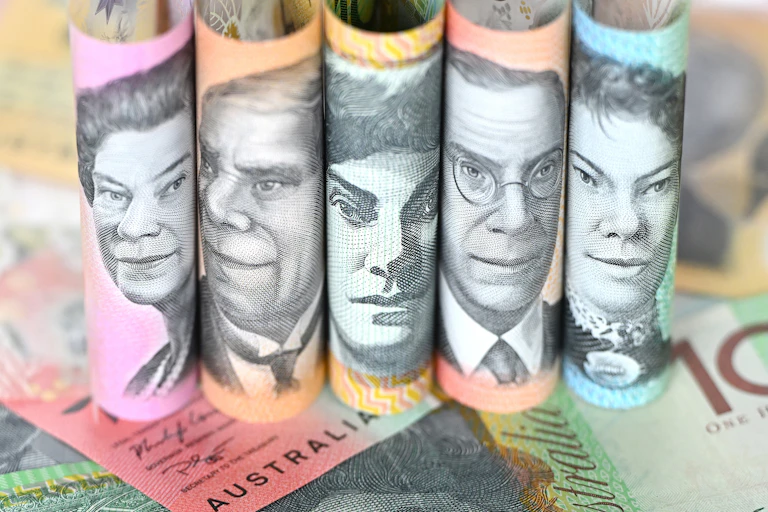 Rolled up Australian currency notes sitting on top of other notes lying flat