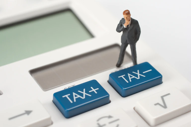 Tax concept - think figurine stand on calculator near tax buttons.
