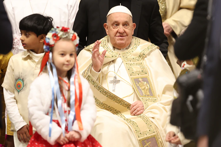 The pope waves at a ceremony with children nearby.