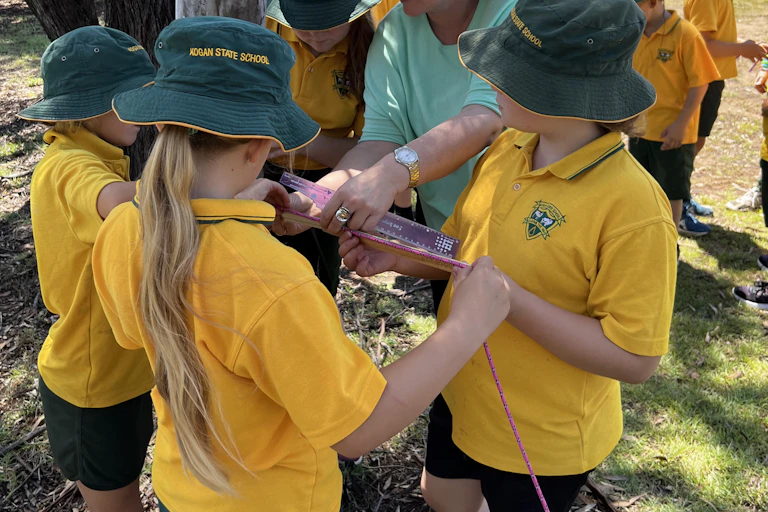Kids in green hats and yellow tops with teacher outside