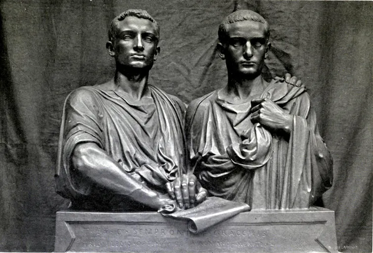 Estatua de dos hombres juntos, sosteniendo un documento.
