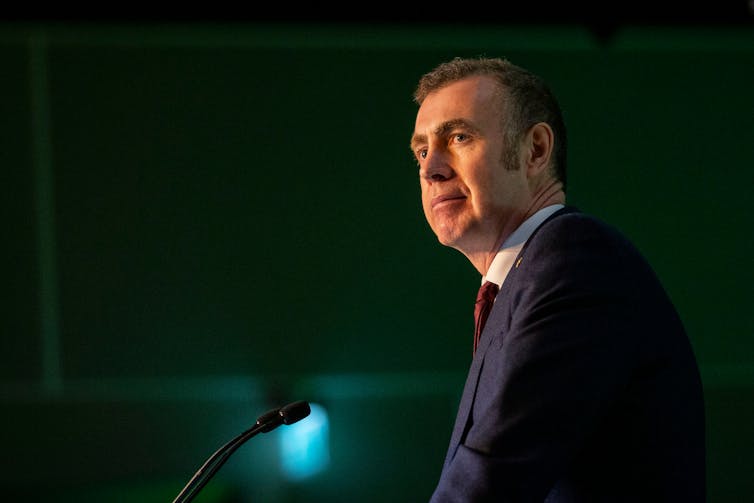 Plaid Cymru MS Adam Price stands at a lectern.