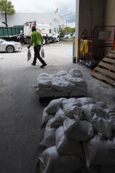 A man carries sandbags from a warehouse to people waiting in cars