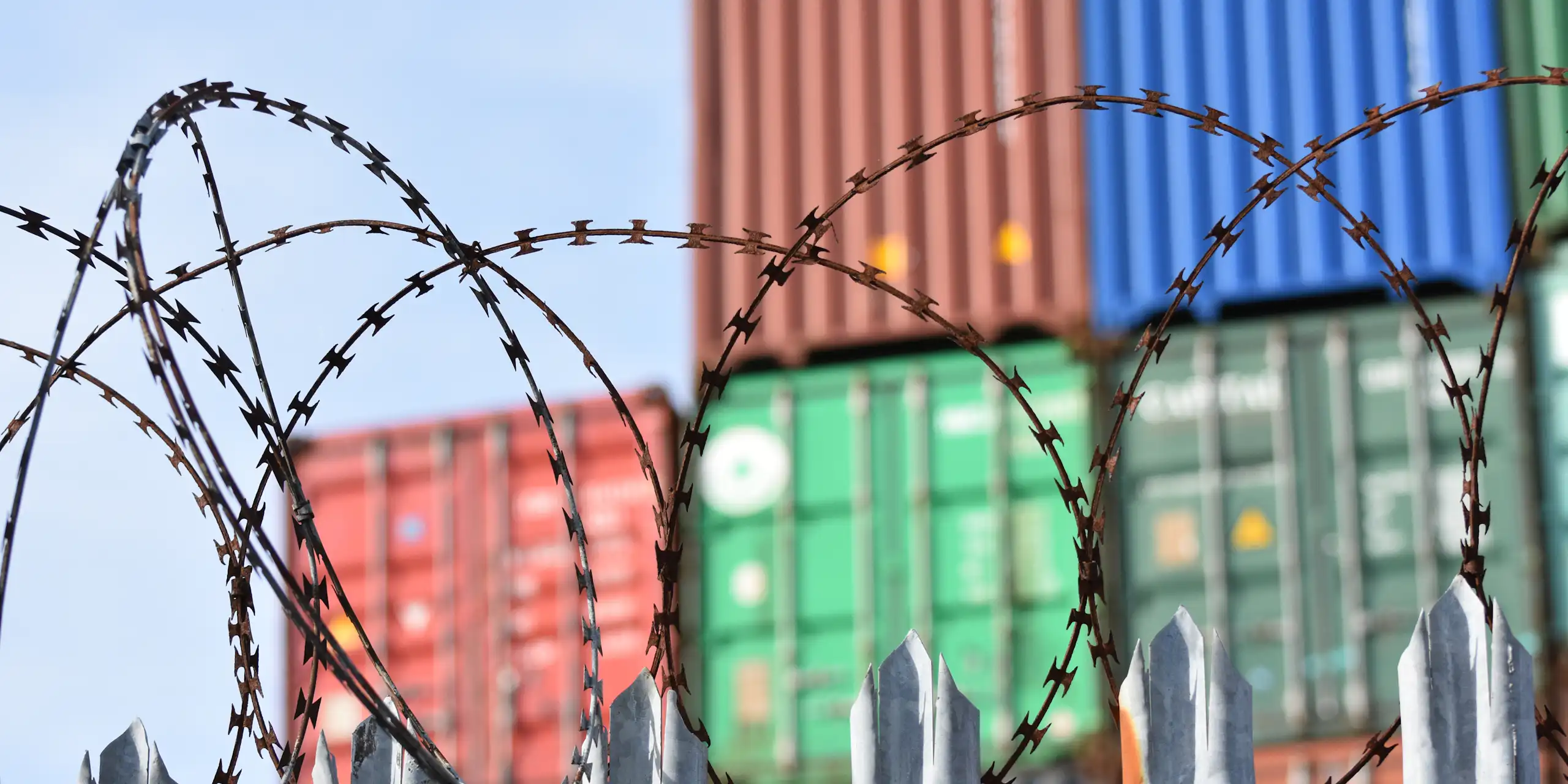 Shipping containes with barbed wire in front.