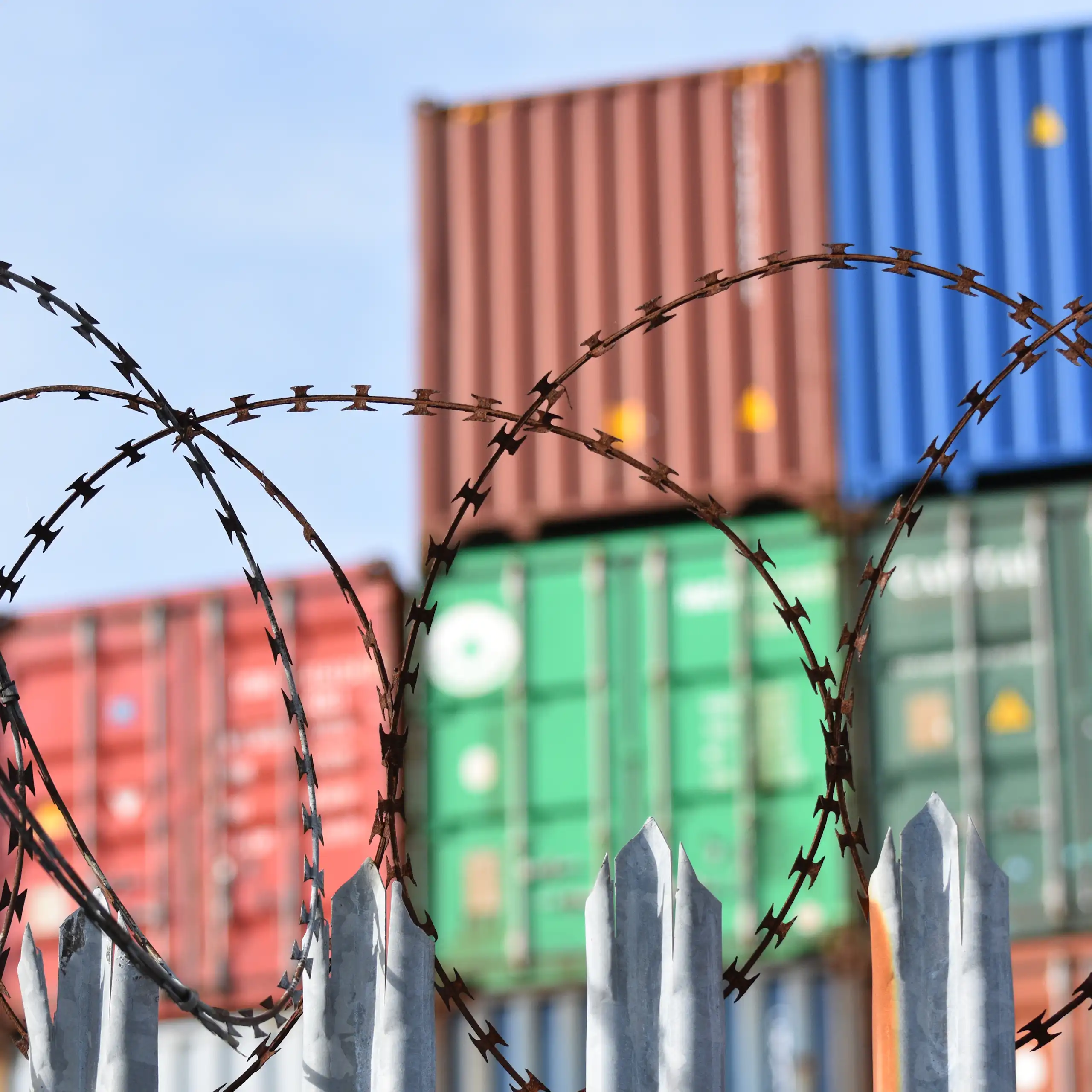 Shipping containes with barbed wire in front.