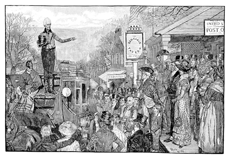 A man stands on the seat of a stagecoach addressing a crowd.