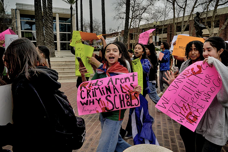 Students seen with signs like 'kids aren't criminals why schools.'