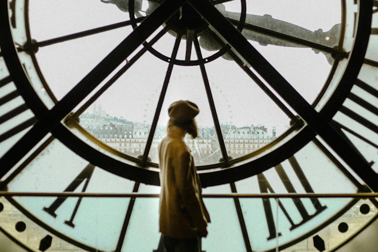 Femme portant un béret à l'intérieur du musée d'Orsay, devant une horloge